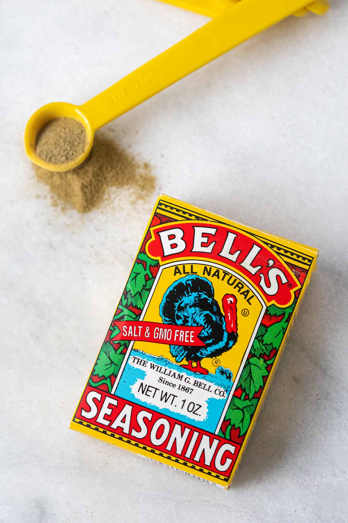 A box of Bell's seasoning with a partially filled measuring spoon beside it.