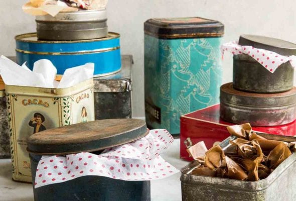 An assortment of holiday cookie tins with tissue paper sticking out of them..