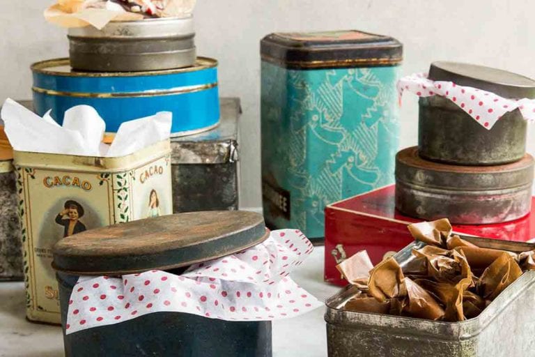 An assortment of holiday cookie tins with tissue paper sticking out of them..