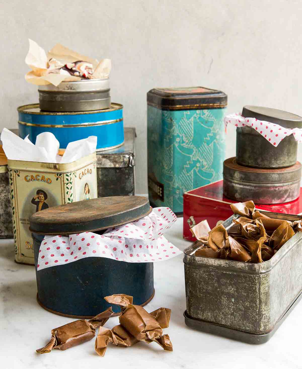 An assortment of holiday cookie tins with tissue paper sticking out of them.