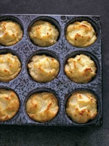 A muffin tin filled with cooked Thanksgiving leftovers muffins.