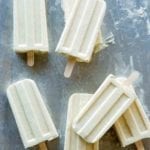 Three eggnog ice pops with wooden popsicle sticks.