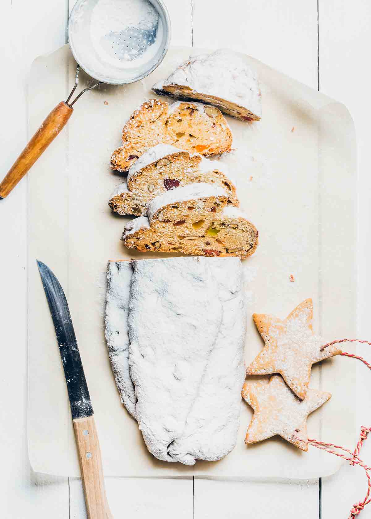 A loaf of Stollen, cut in half with a slice cut off to reveal the fruit and marzipan filling.