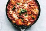 A metal skillet filled with easy skillet lasagna and garnished with basil leaves.