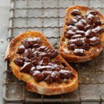 Two slices of sourdough toast topped with melted bits of chocolate and sprinkled with sea salt.