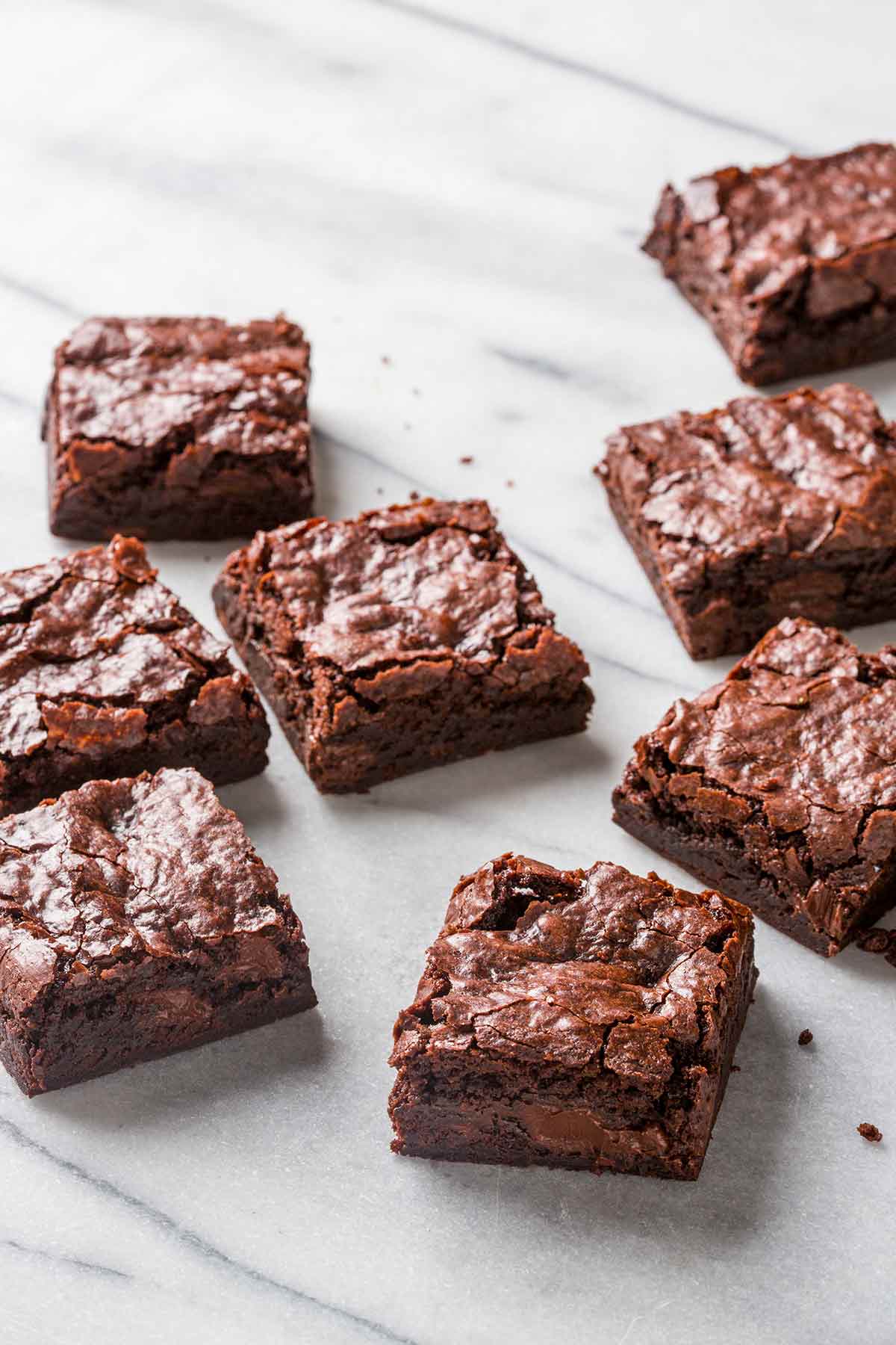 Eight vegan fudge brownies on a marble surface.