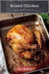 A perfect roast chicken in a metal roasting pan that is resting on a kitchen towel, with a bunch of herbs beside it.