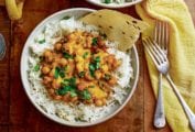 Two bowls of rice and curried chickpeas with two forks and a yellow cloth on the side.