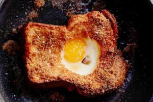 A slice of toast in a skillet with an egg in the hole of the toast.