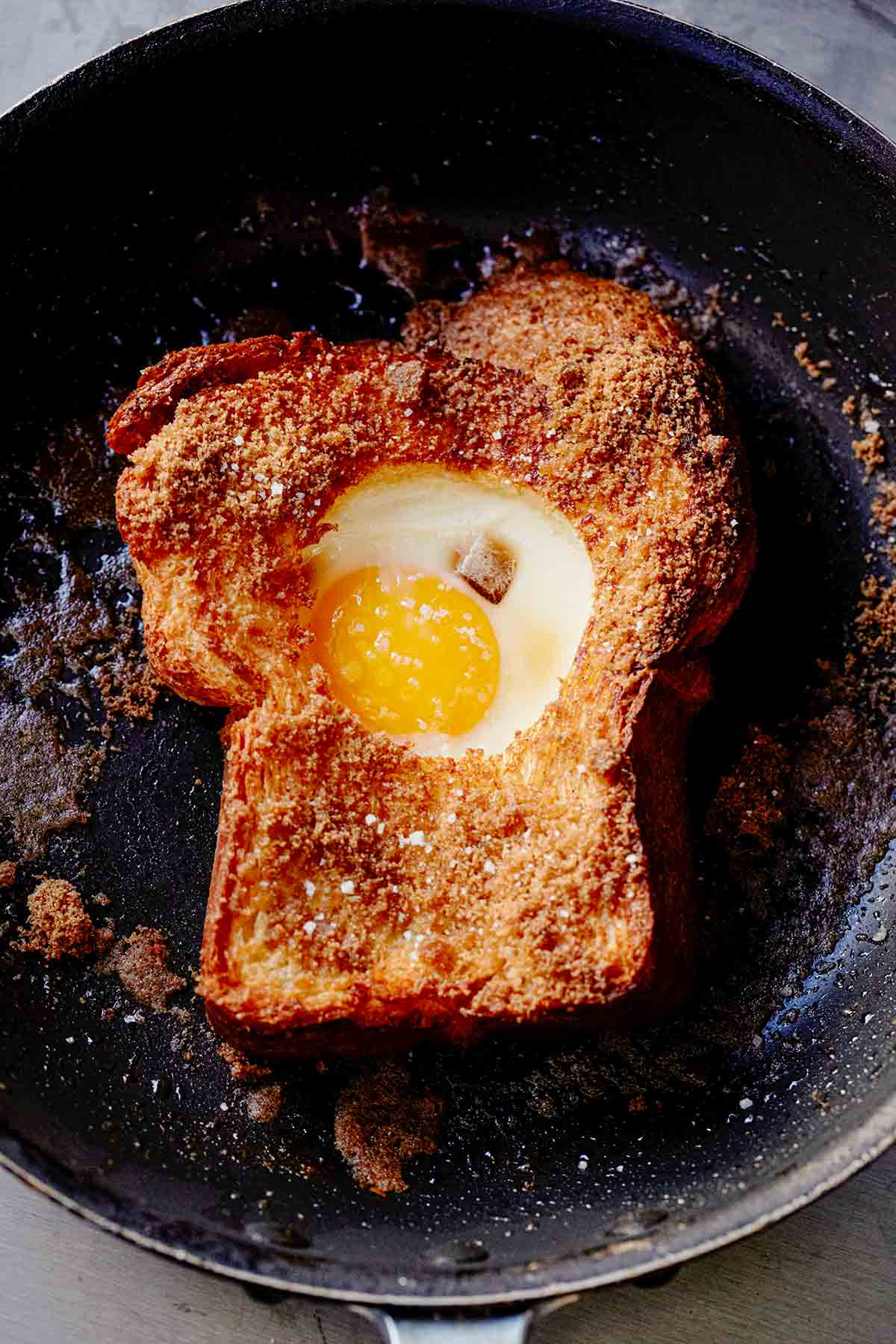 A slice of toast in a skillet with an egg in the hole of the toast.