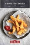 A pile of fancy fish sticks on a piece of parchment with a dollop of ketchup beside them.