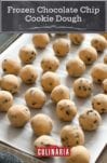 Balls of frozen chocolate chip cookie dough on a parchment-lined baking sheet.