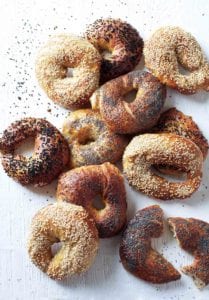 A variety of homemade bagels on a white surface.