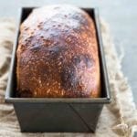 A browned loaf of homemade sandwich bread in a metal loaf tin.