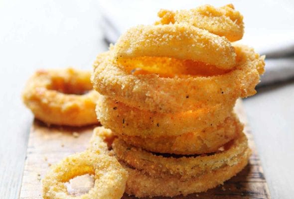 A stack of moonshine onion rings on a wooden board.