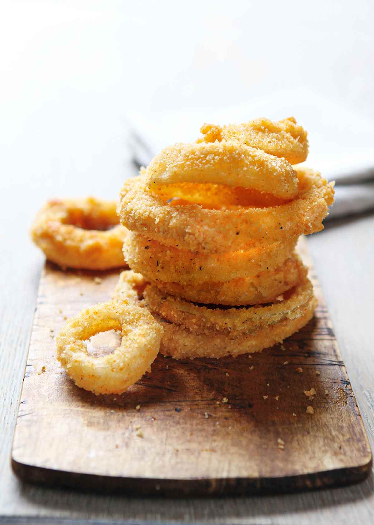 A stack of moonshine onion rings on a wooden board.