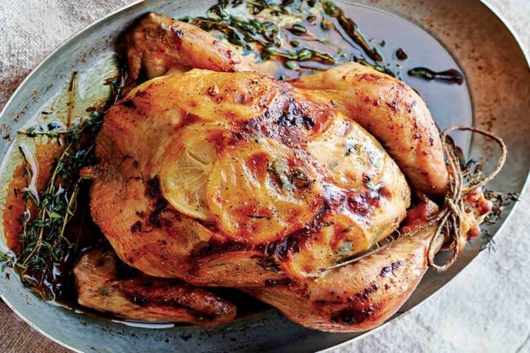 Roast chicken with lemon slices under the skin in a oval metal pan