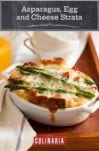 A white oval casserole filled with asparagus, egg and cheese strata--bread, Fontina cheese, eggs, prosciutto, and asparagus