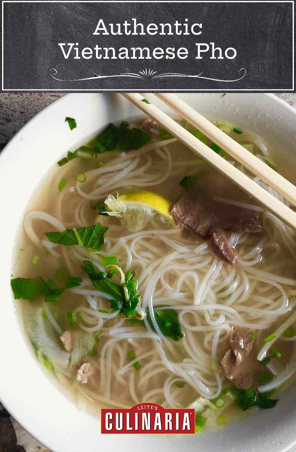 A bowl of authentic Vietnamese pho with rice noodles, beef, lemon, basil, and scallions in it and a pair of chopsticks resting on top of the bowl.