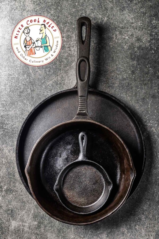 Three cast iron skillets of varying sizes on a gray badkground.