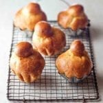 Five classic brioche rolls on a wire rack, three in metal tins, two removed from the tins.