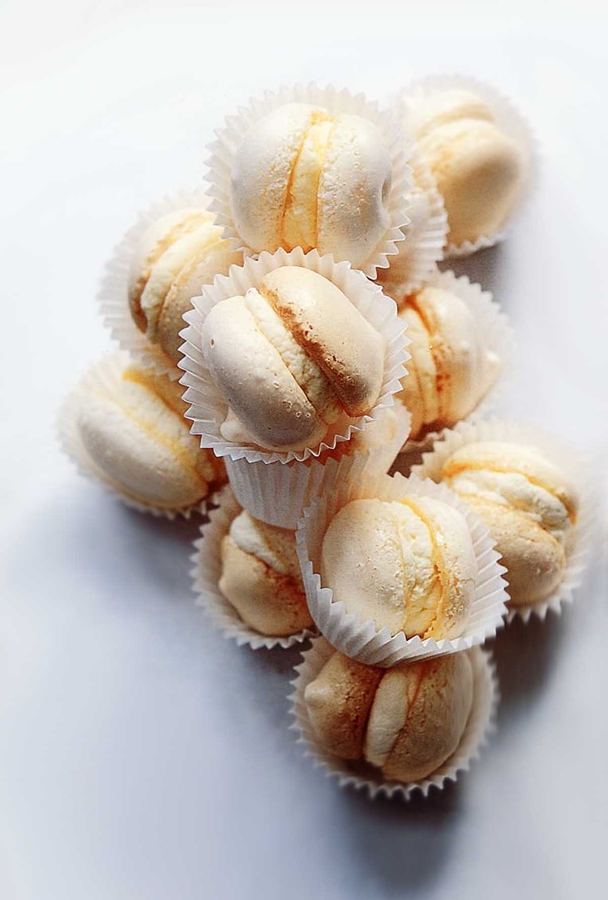 A pile of cream-filled macarons, each in a white wrapper.