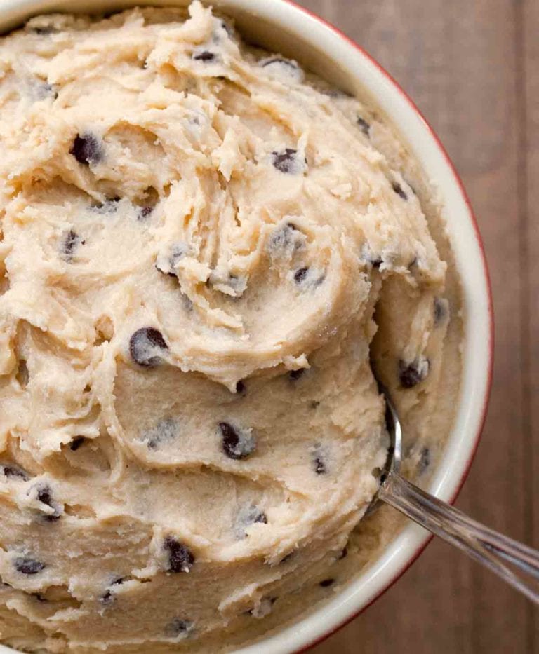 A bowl of eggless chocolate chip cookie dough with a spoon resting in it.