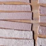 Strips of homemade red wine pasta on a wooden surface.
