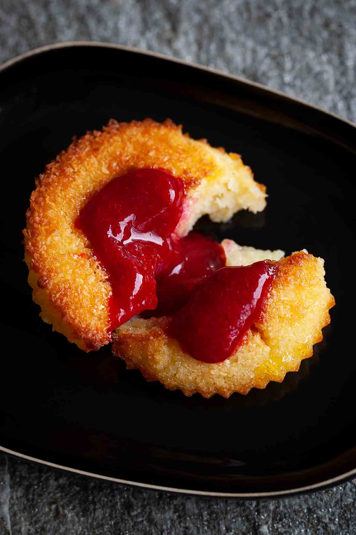 A halved Portuguese coconut custard tart on a black plate.