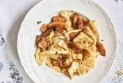 A white dinner plate filled with strapponi pasta with porcini mushrooms and mint.