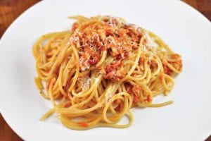A tangle of tomato and tuna spaghetti on a white plate.