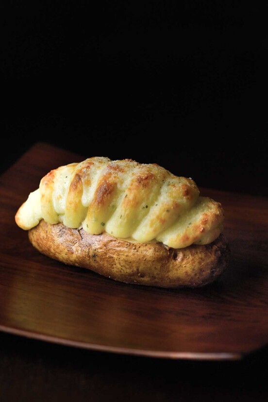 A twice-baked potato with Irish Cheddar on a dark wood table.