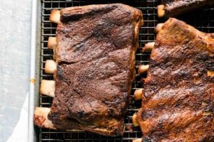 Four slabs of BBQ oven ribs on a rack inside a rimmed baking sheet.