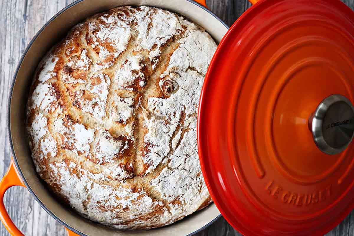 A loaf of baked bread in a Le Creuset Dutch oven.