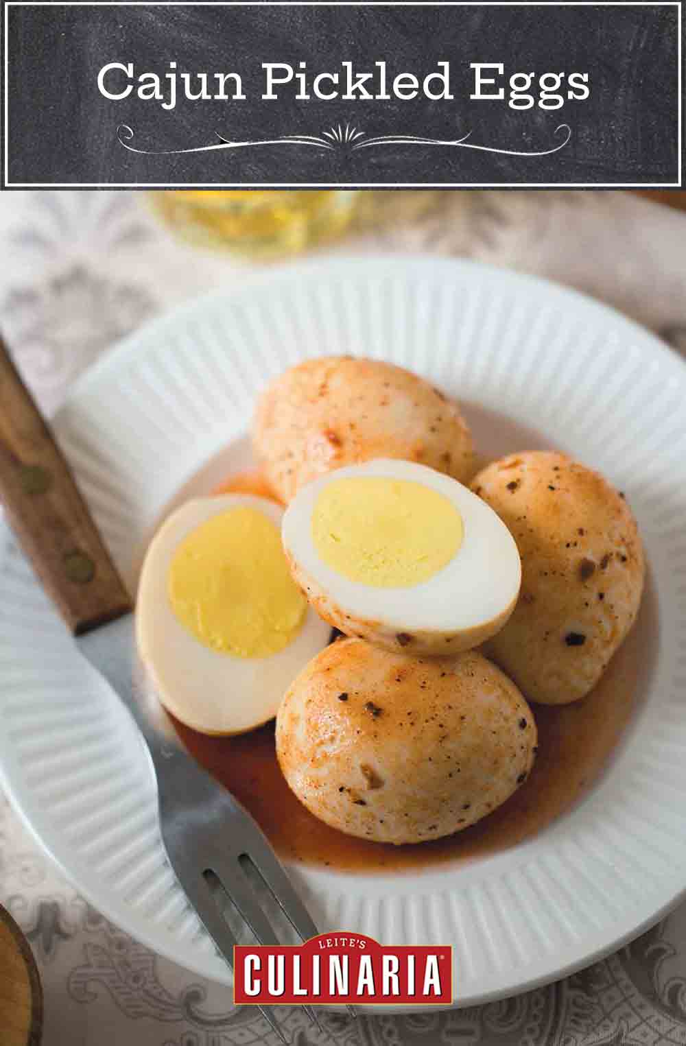 A white plate topped with four Cajun pickled eggs, one of which is cut in half. A fork rests on the plate.