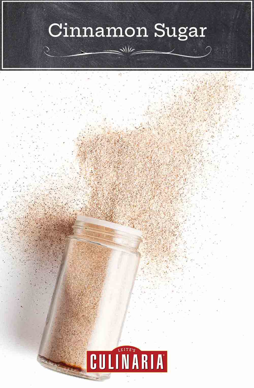 A glass spice jar filled with cinnamon sugar, lying on its side with some cinnamon sugar poured out.