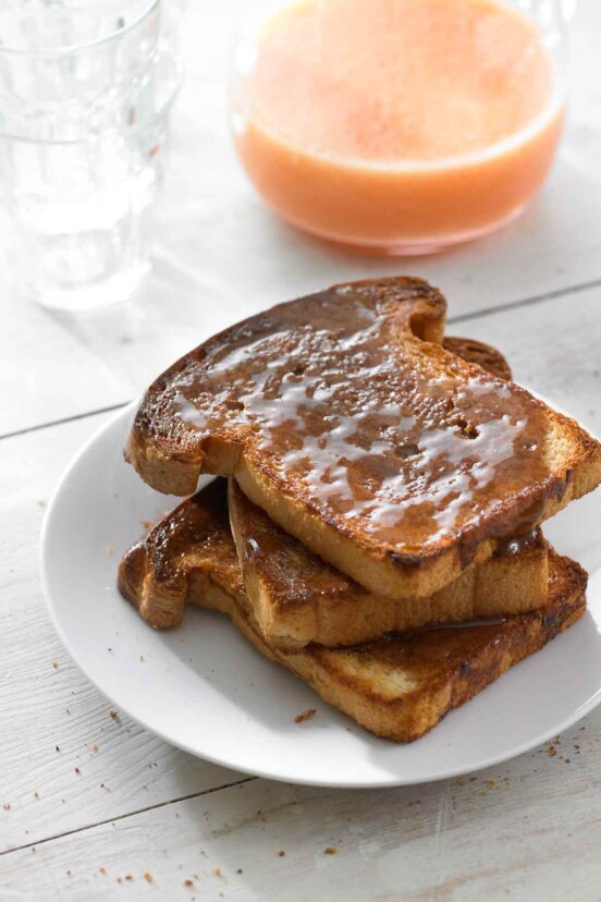 Three slices of cinnamon toast stacked on a white plate.