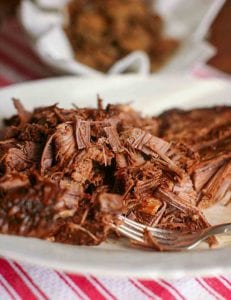 A plate of shredded Coca-Cola brisket with a fork resting in the meat.