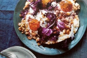 A blue plate topped with two fried eggs with crisp bread crumbs and radicchio.