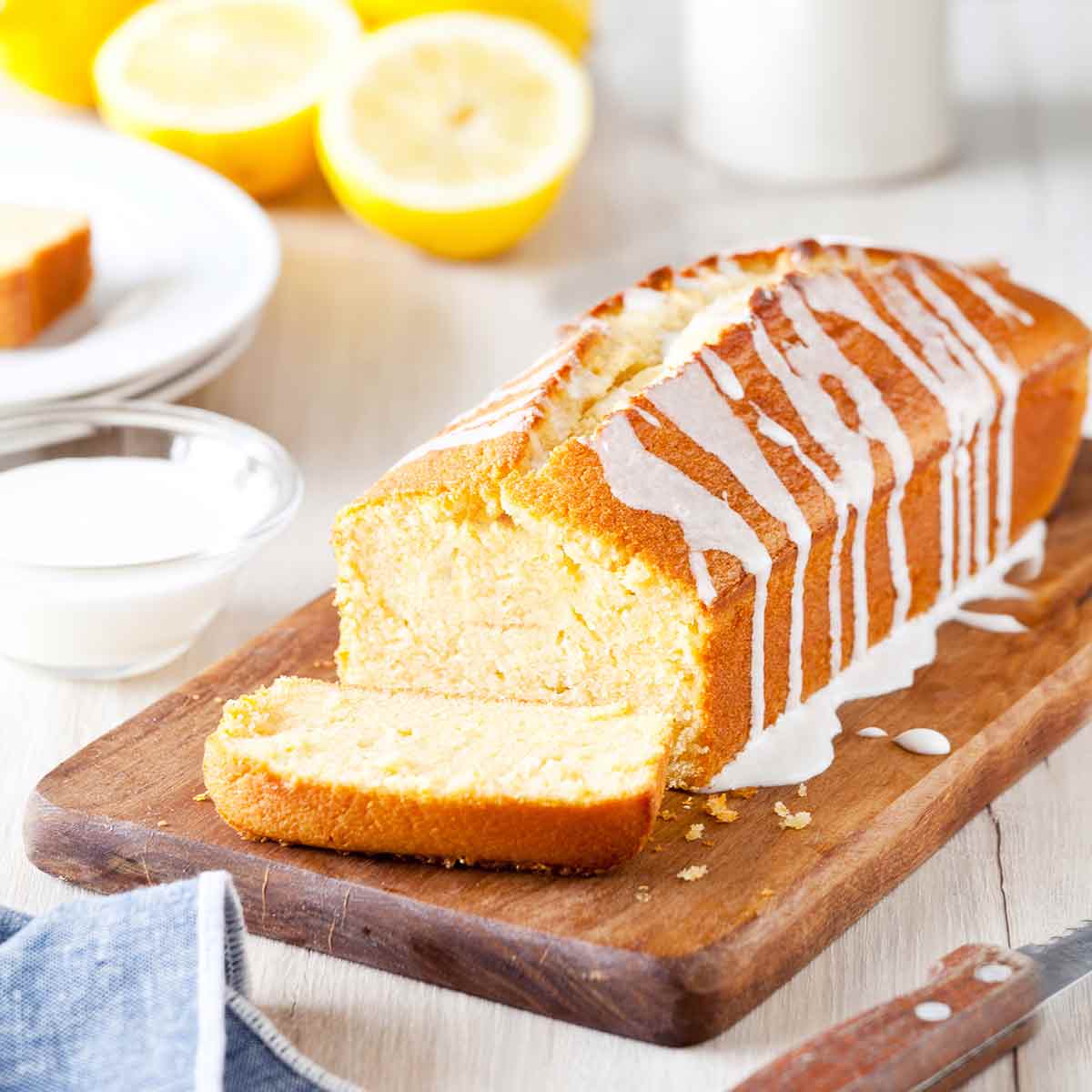 Ina Garten's lemon cake, a pound cake, on a cutting board, drizzled with a lemon glaze