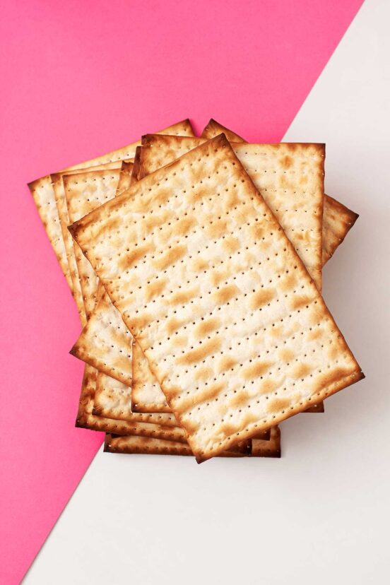 A pile of matzoh on a pink and white background.