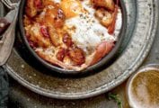 A bowl of patatas bravas with ham and egg - crispy potatoes, ham, and fried egg - with a fork resting beside it.