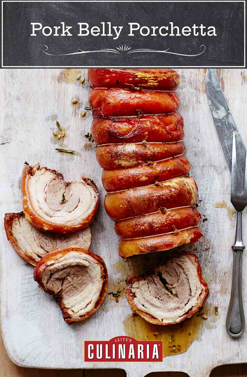 A pork belly porchetta on a cutting board with four slices carved from the end and a carving fork and knife resting beside the meat.