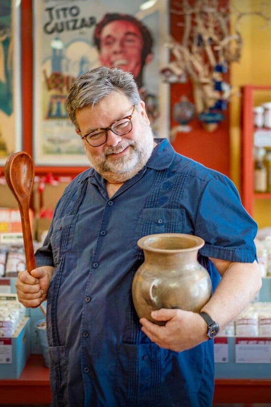 Steve Sando holding an earthenware vessel and wooden spoon.