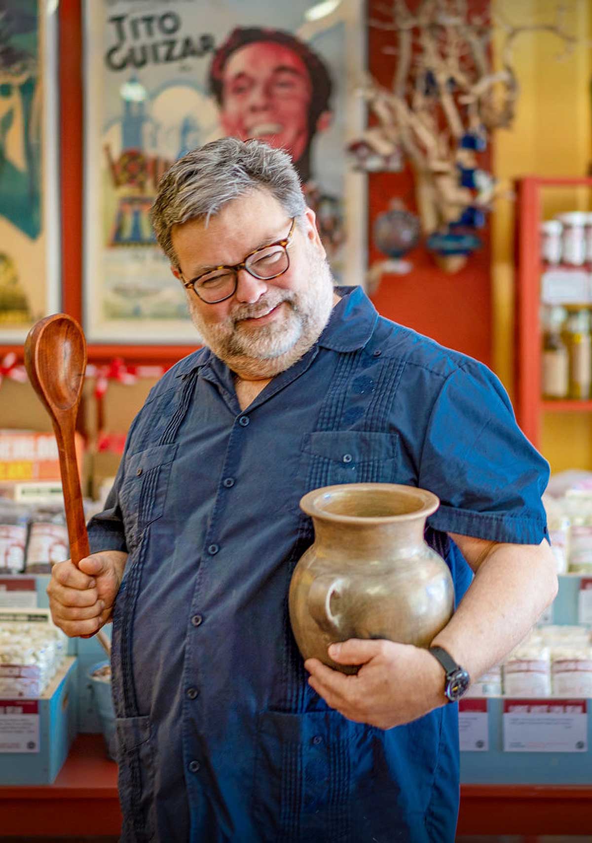 Steve Sando holding wooden spoon and ceramic pot.