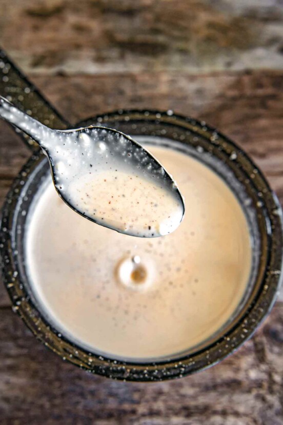 A spoonful of Alabama white bbq sauce above a jar of it.