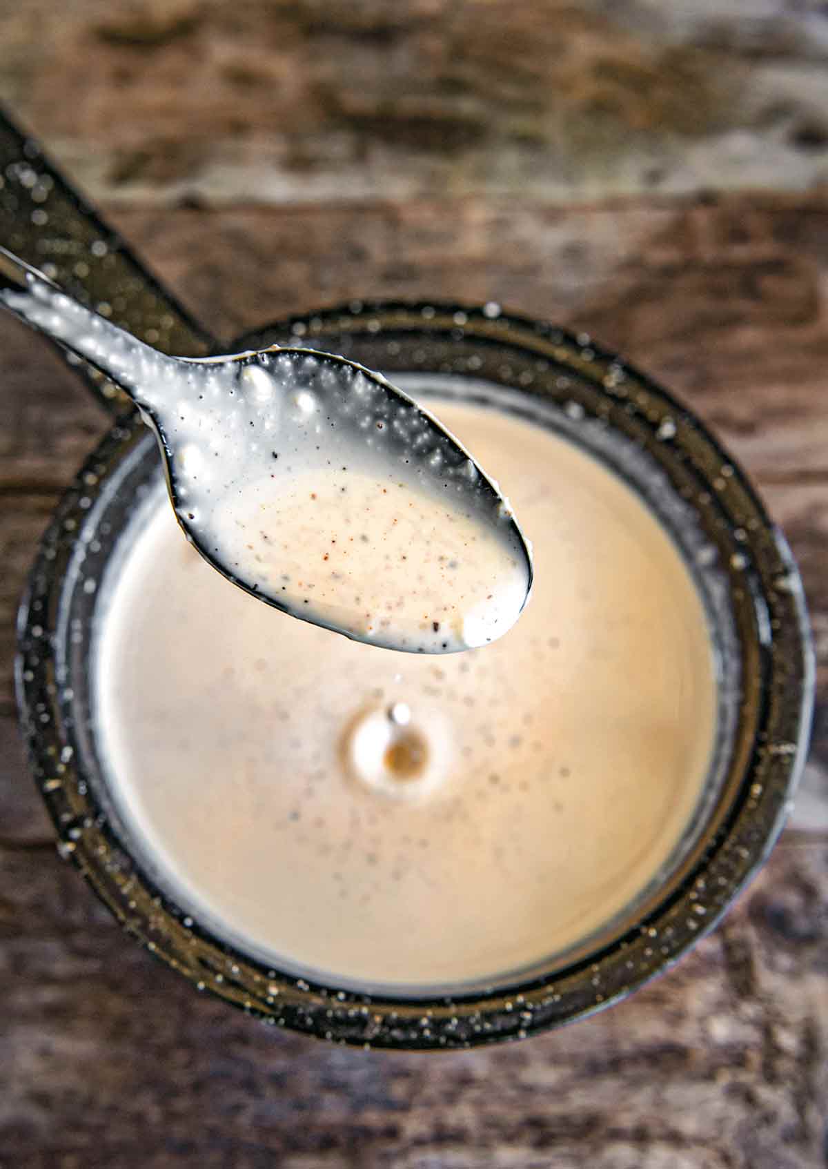 A spoonful of Alabama white bbq sauce above a jar of it.