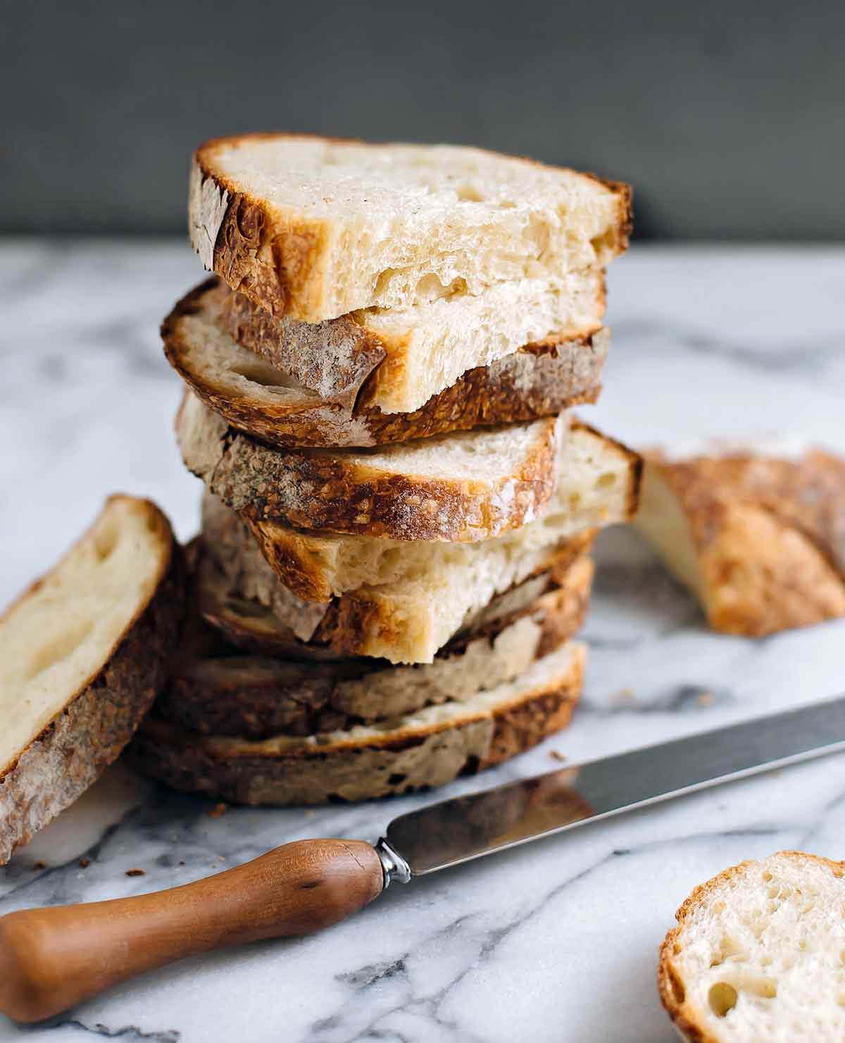 Halved slices of sourdough stacked on top of each other on a white and grey marble surface.