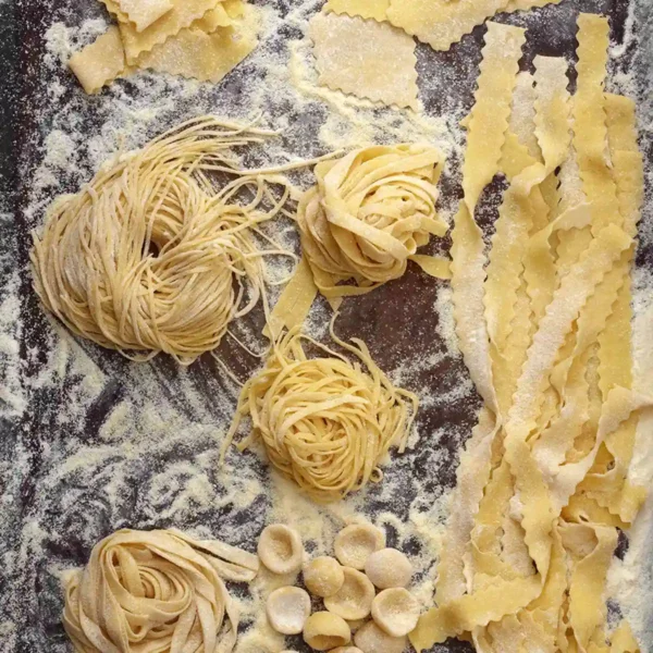 A pan full of tagliatelle spaghetti, bowl-shaped orecchiette and other handmade pasta shapes.