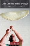 A thin circle of stretched pizza dough being tossed in the air.